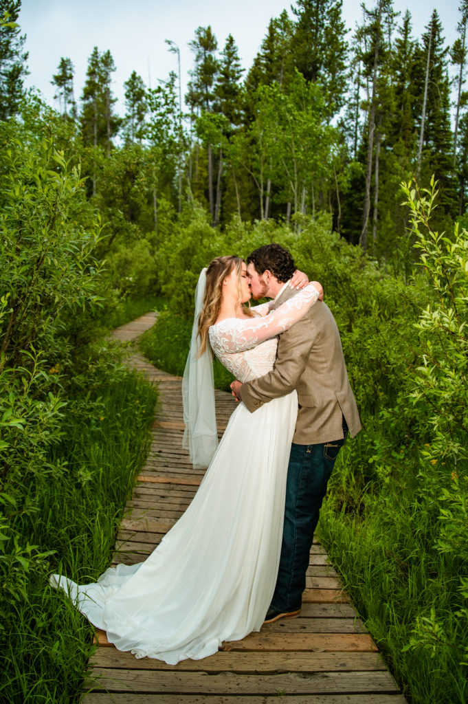 Jackson Hole wedding photographers capture couple kissing in green forest of Jackson Hole 