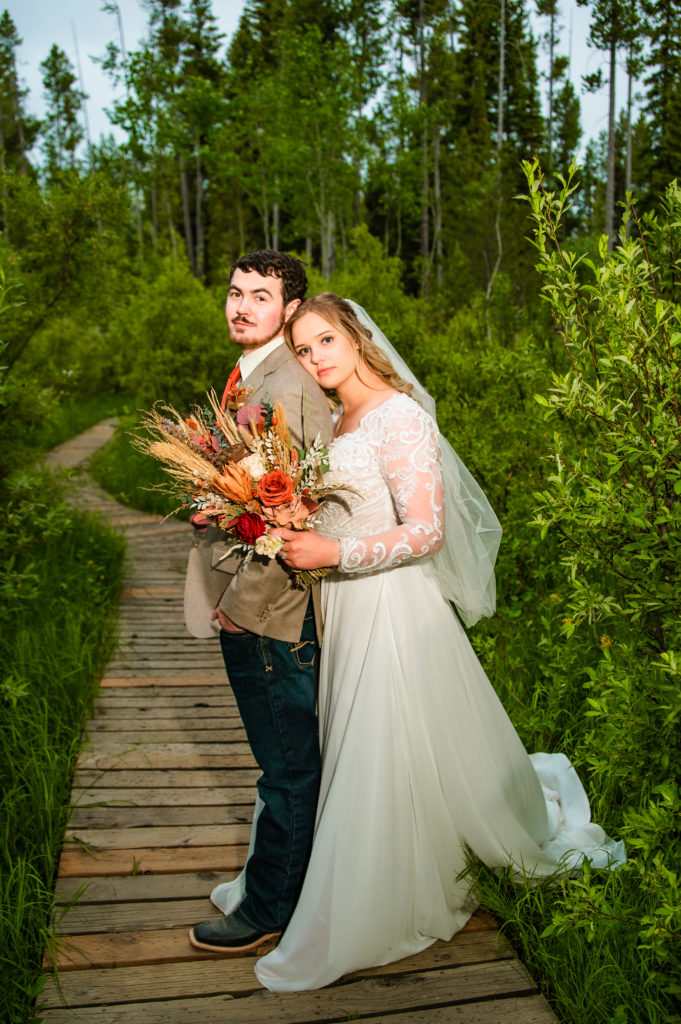 Jackson Hole wedding photographers capture bride leaning on groom during outdoor portraits