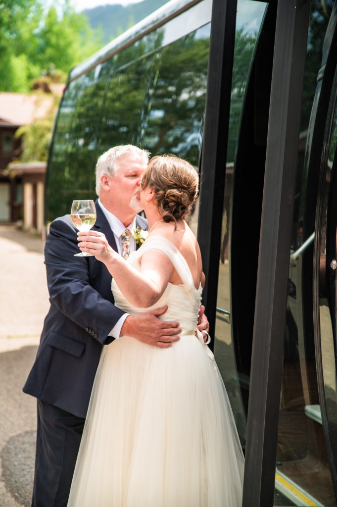 Jackson Hole wedding photographers capture bride and groom kissing outside party bus before Jackson Hole wedding