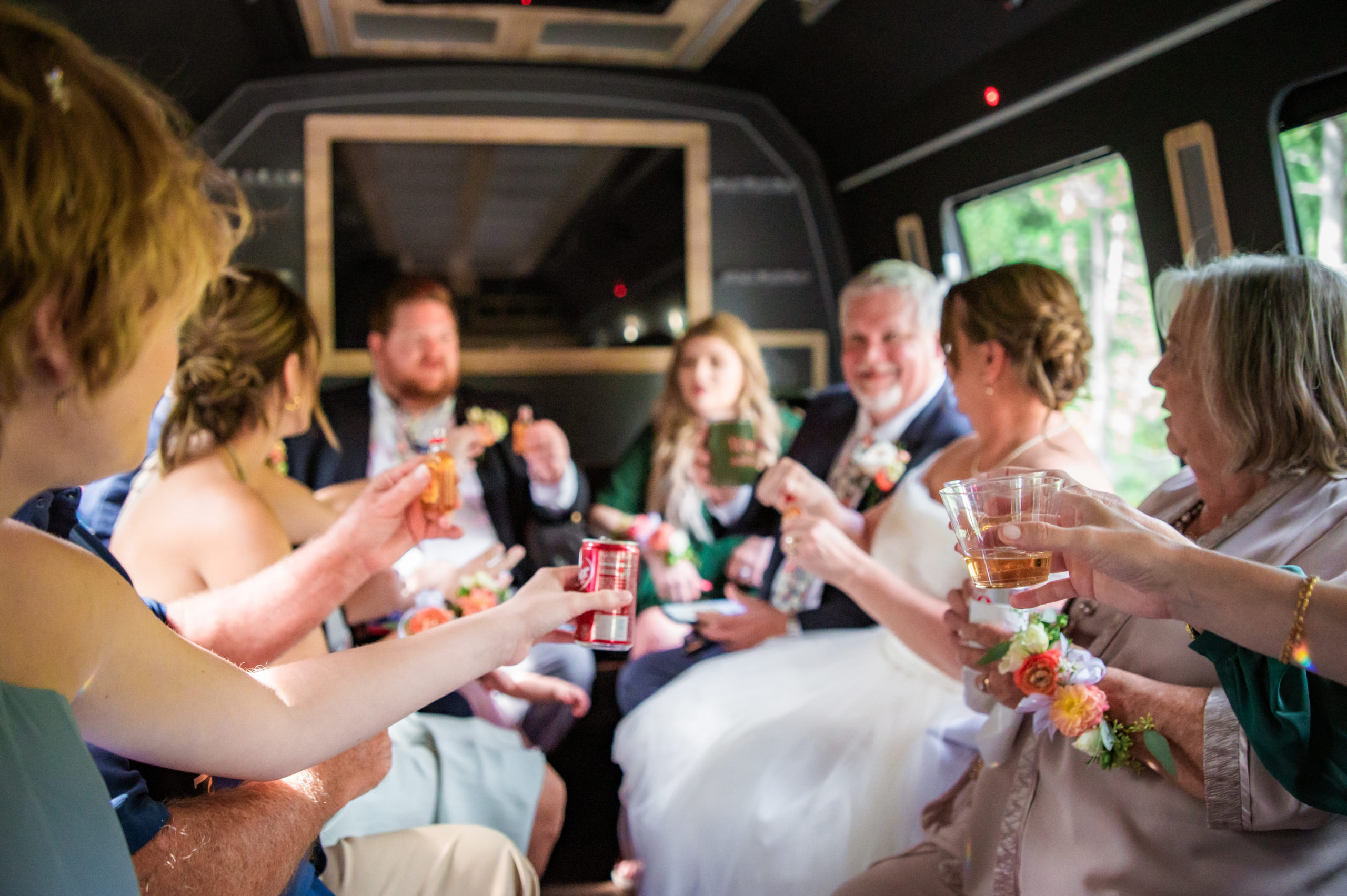 Jackson Hole wedding photographers capture wedding party toasting with soda in party bus before Grand Teton wedding