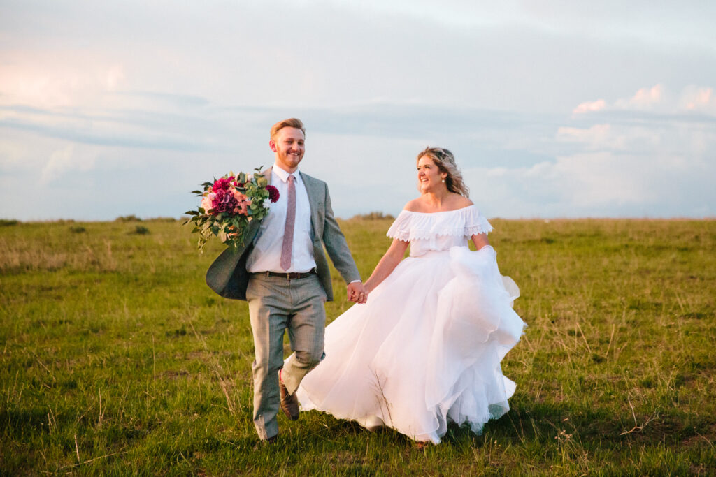 Jackson Hole elopement photographer captures bride and groom running down hill hand in hand after elopement