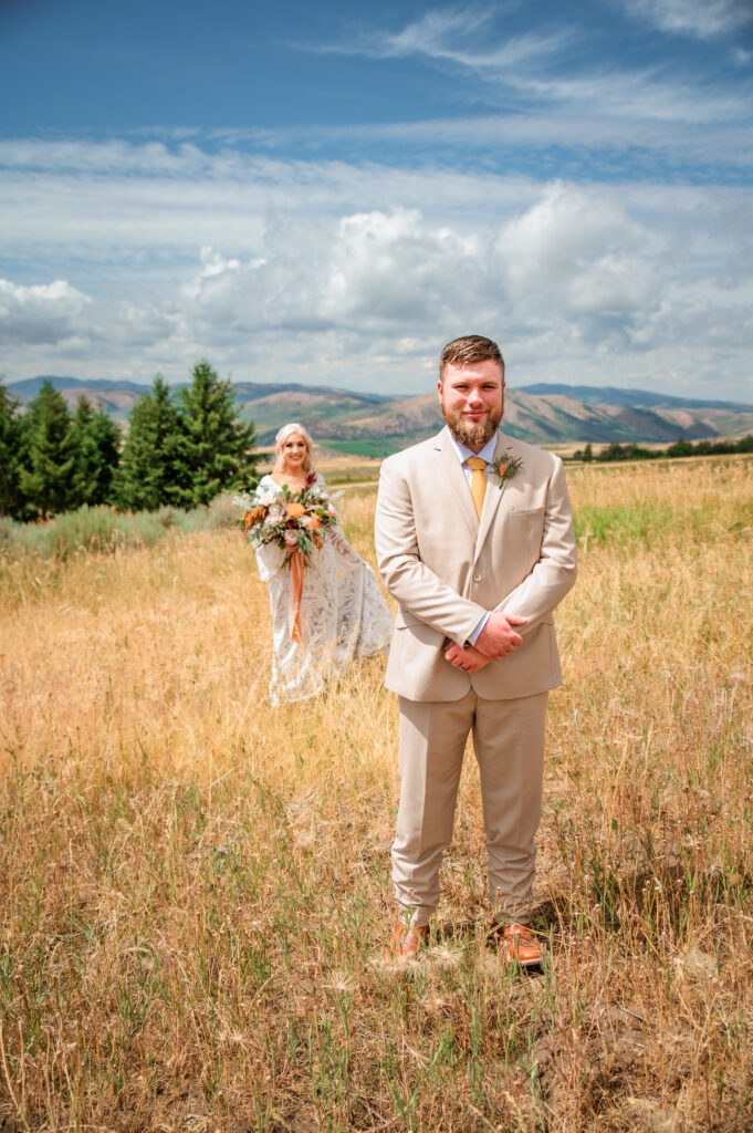 Top Jackson Hole Wedding Photographers capture bride revealing dress to groom in a wild field.