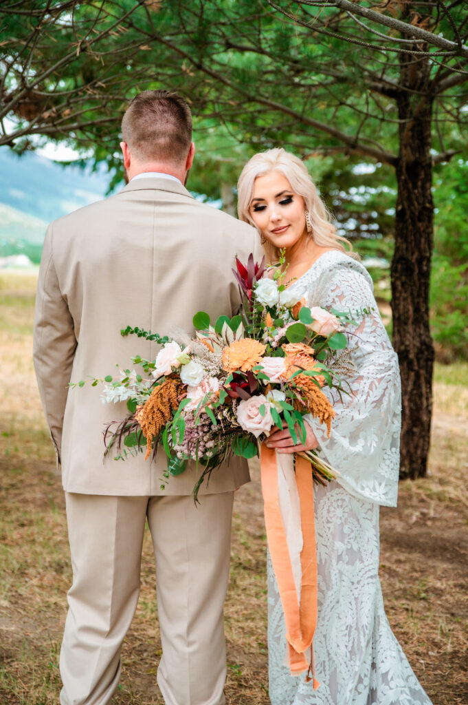 grooms back is turned towards the camera while bride rests her head on his shoulder while showing off her rust and cream bouquet.