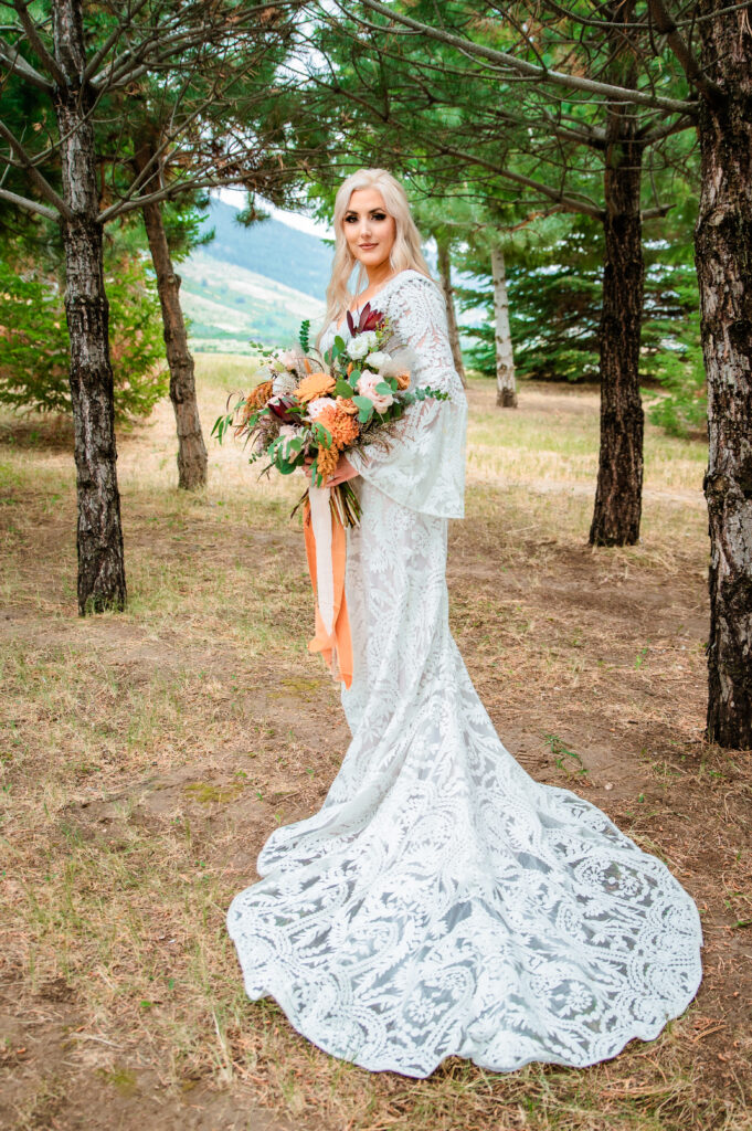 Jackson Hole bride shows off her lacey boho dress and bouquet full of orange and cream tones.