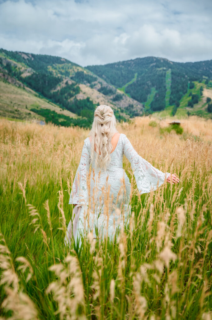 Back of dress details of Jackson Hole bride frolicking through the tall grassy hills.