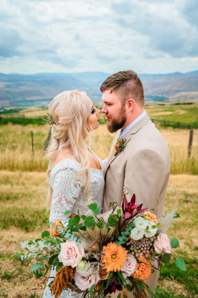 Bride and groom lean in for kiss at Jackson Hole wedding while brides big bouquet frames their bodies.