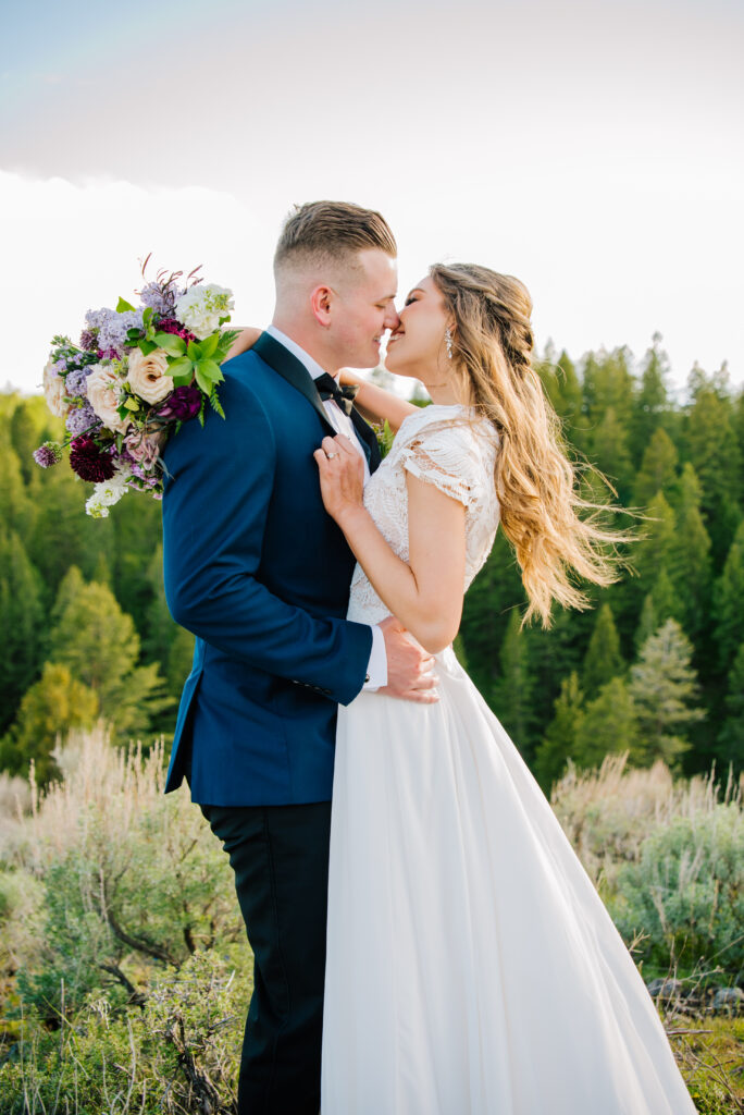 Colorful Grand Teton National Park Wedding smile kisses between groom and bride at their mountain wedding. Groom is in a navy blue and black tux.