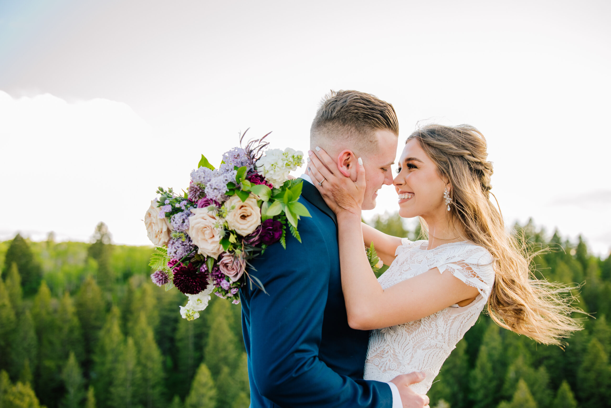 Colorful Grand Teton National Park Wedding bride grabs grooms face and laughs as the wind blows her hair back.