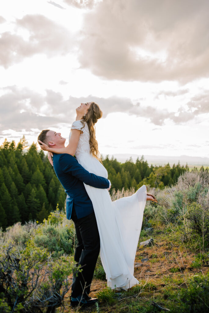 After the colorful Grand Teton Wedding groom lifts bride up into the air. Bride throws her head back and laughs.