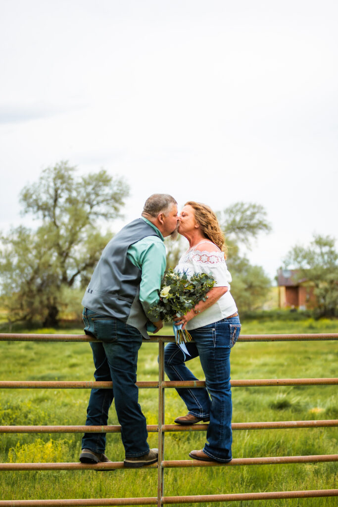 Grand Teton Wedding bride and groom pose on cattle gate kissing.