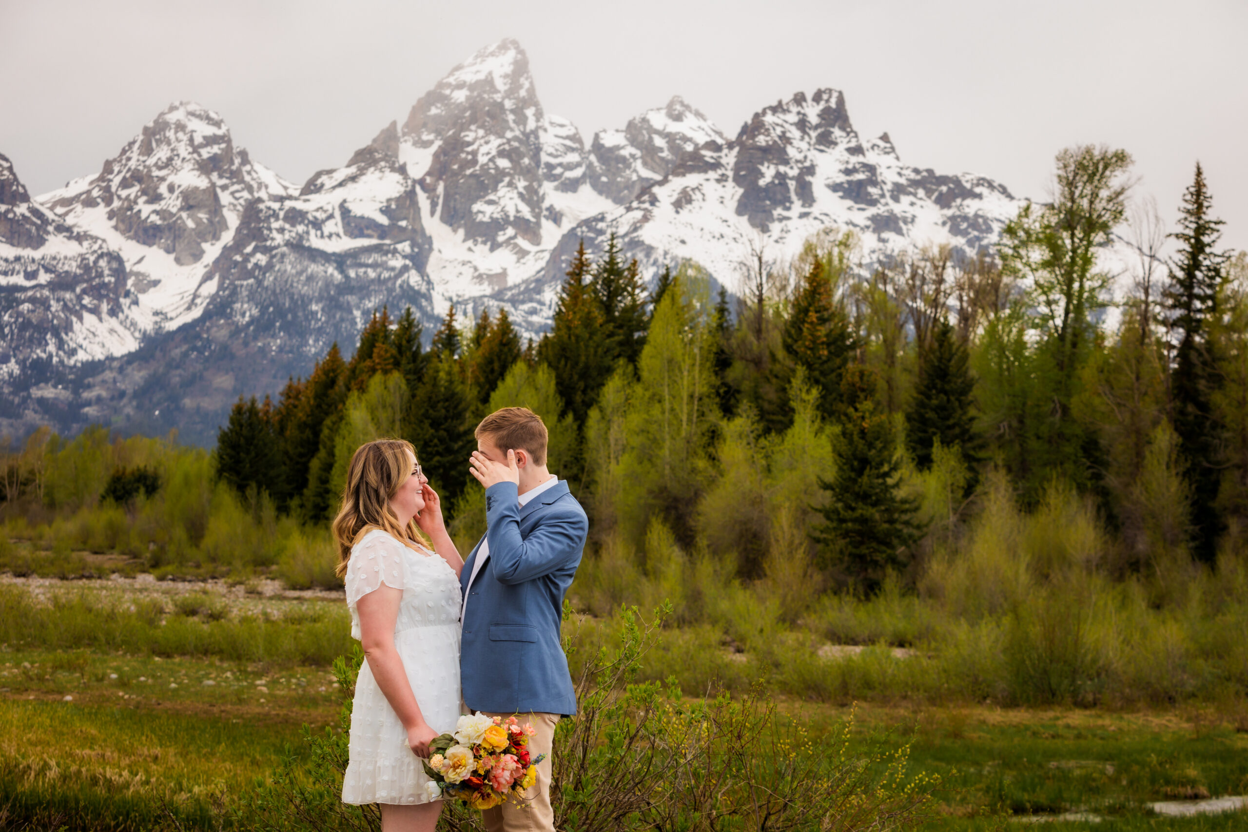Emotional elopement bride and groom cry as they give their vows that leads to giggling. The tetons are snow capped and majestic.