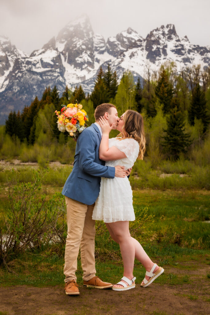 Groom dips bride back for a tender kiss at his minimalistic Jackson Hole elopement while bride tips her toe.