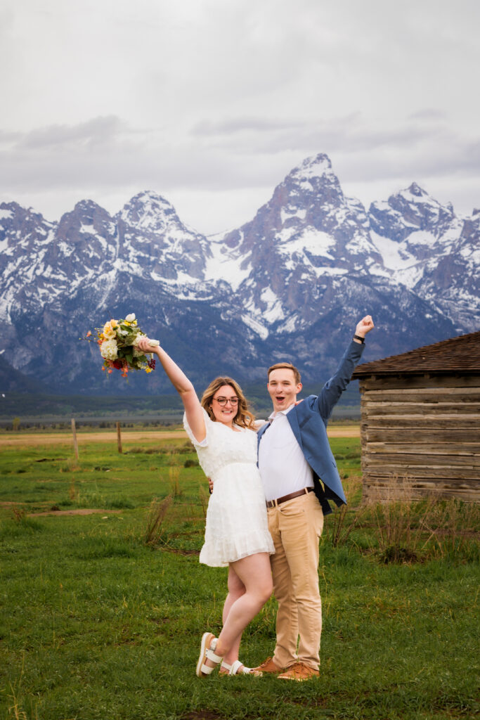 Bride and groom throw their arms in the air to celebrate their 2024 gtnp elopement